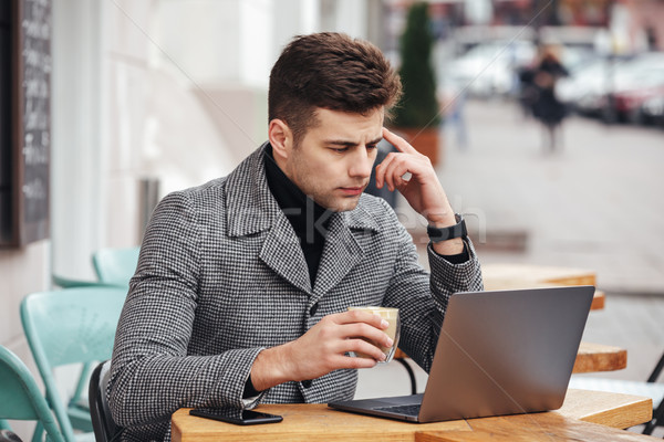 Portrait of working man sitting with silver laptop in cafe outsi Stock photo © deandrobot