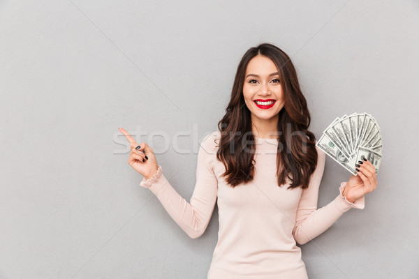 Successful brunette girl holding fan of 100 dollar bills being r Stock photo © deandrobot