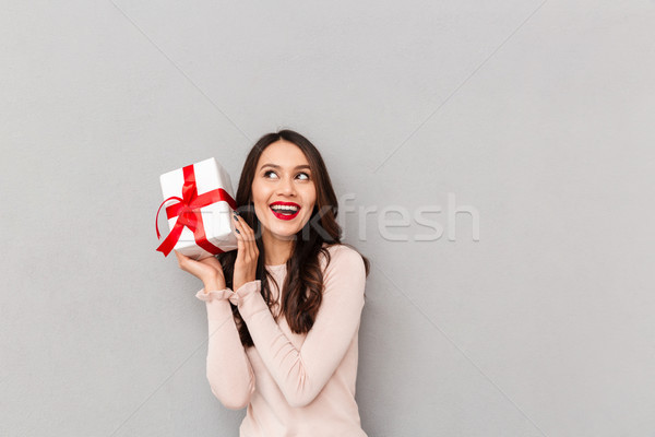 Image of lucky woman holding bithday present with red bow being  Stock photo © deandrobot