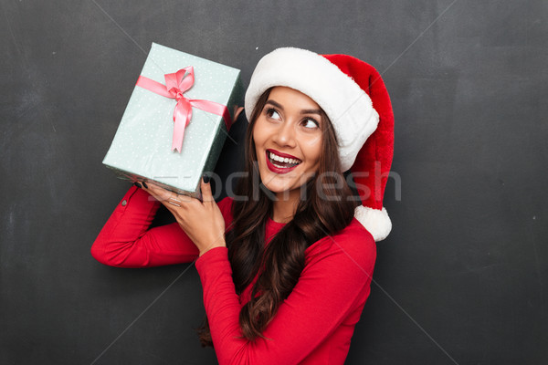 Cheerful intrigued brunette woman in red blouse and christmas hat Stock photo © deandrobot