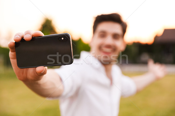 Man outdoors take a selfie by mobile phone. Stock photo © deandrobot
