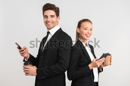 Smiling businessman in a suit giving you a smartphone over white background Stock photo © deandrobot