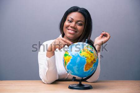 African businesswoman sitting at the table with globe Stock photo © deandrobot