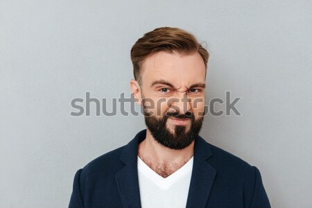 Dissatisfied frowning handsome young man with beard in sweetshirt  Stock photo © deandrobot