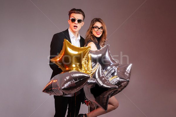 Beautiful young couple standing and holding star shaped balloons Stock photo © deandrobot