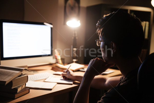 Man in glasses sitting and using computer for studying Stock photo © deandrobot