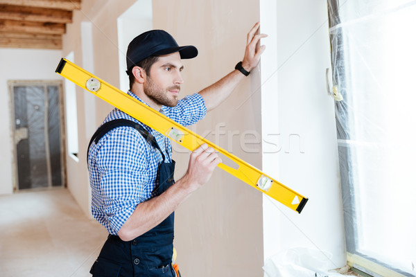 Concentrated repairman standing with a level Stock photo © deandrobot