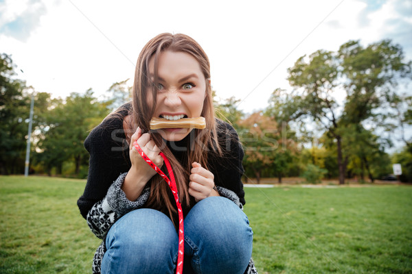 Funny young woman holding bone in mouth playing with dog Stock photo © deandrobot