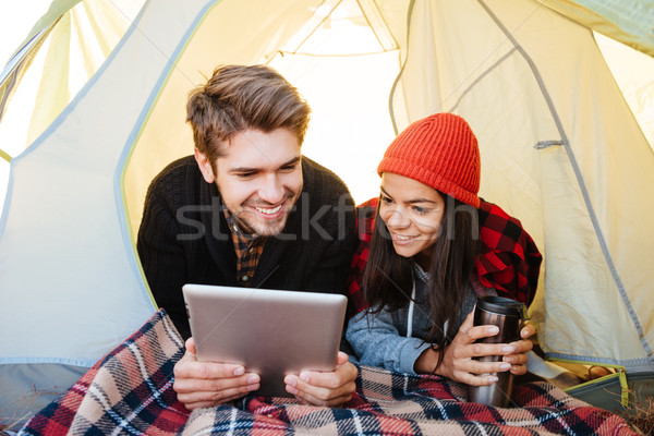Happy couple lying in tent and using tablet computer Stock photo © deandrobot