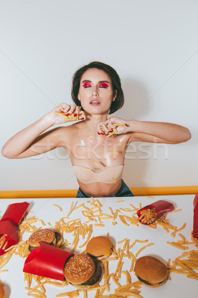 Seductive young woman holding french fries at the table Stock photo © deandrobot