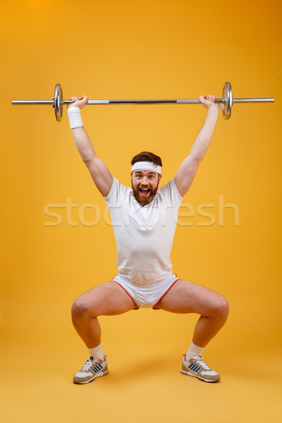 Full length portrait of a fitness man squatting with barbell Stock photo © deandrobot