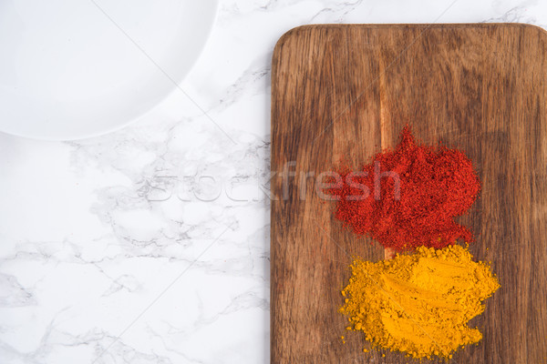 Top view of two turmeric and paprika heaps over wooden Stock photo © deandrobot