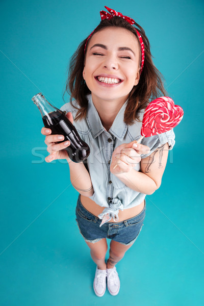 Happy young lady eating candy and holding aerated sweet water. Stock photo © deandrobot