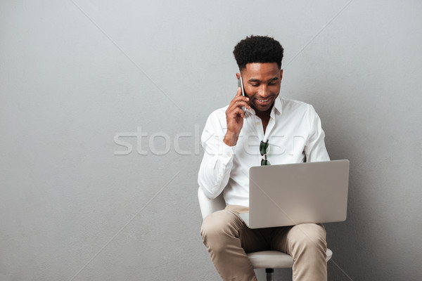 Attractive young african man holding laptop computer on his lap Stock photo © deandrobot