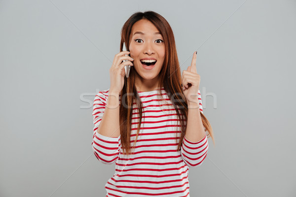 Happy young asian woman talking by phone have an idea. Stock photo © deandrobot