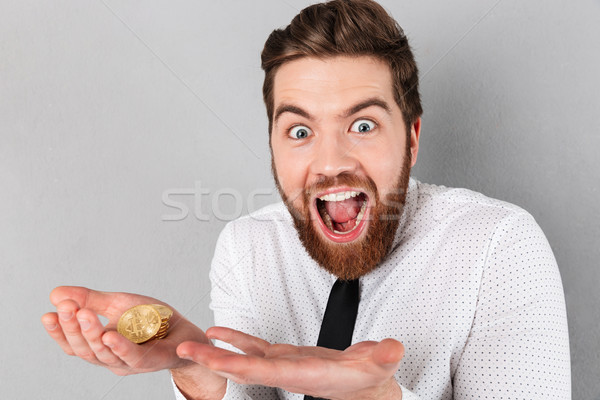 Portrait of an excited businessman showing golden bitcoins Stock photo © deandrobot