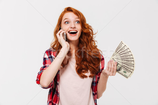 Happy surprised ginger woman in shirt talking by smartphone Stock photo © deandrobot