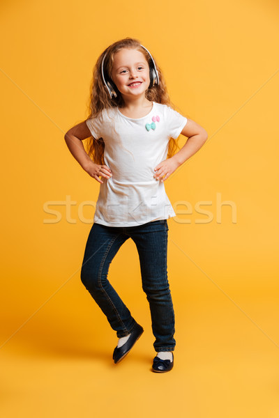 Cheerful girl dancing isolated listening music with headphones. Stock photo © deandrobot