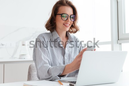 Photo of young concentrated woman in striped shirt using laptop  Stock photo © deandrobot