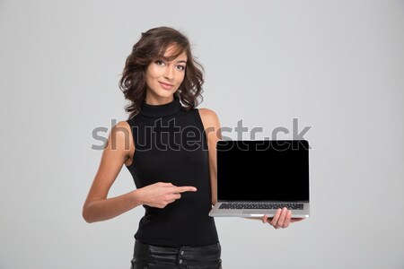 Smiling young woman pointing on blank laptop computer screen Stock photo © deandrobot
