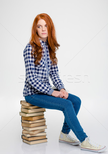 Thoughtful woman with red hair sitting on books and thinking Stock photo © deandrobot