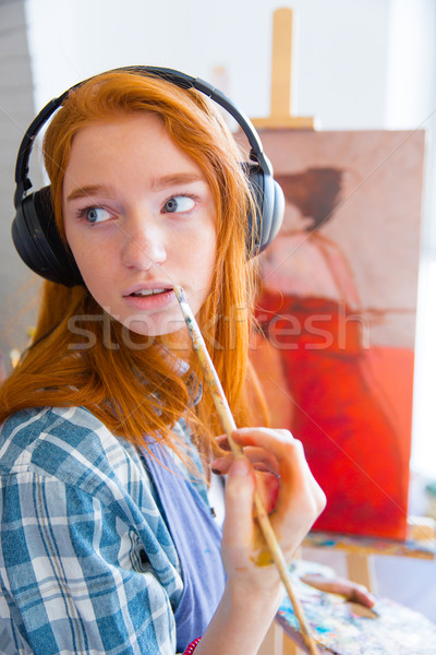 Thoughtful attractive young female painter listening to music and painting Stock photo © deandrobot