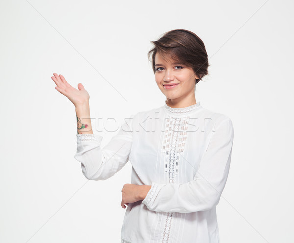 Smiling charming young female holding copyspace on palm  Stock photo © deandrobot