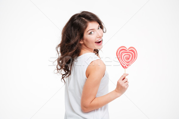 Happy woman holding lollipop and looking back at camera Stock photo © deandrobot