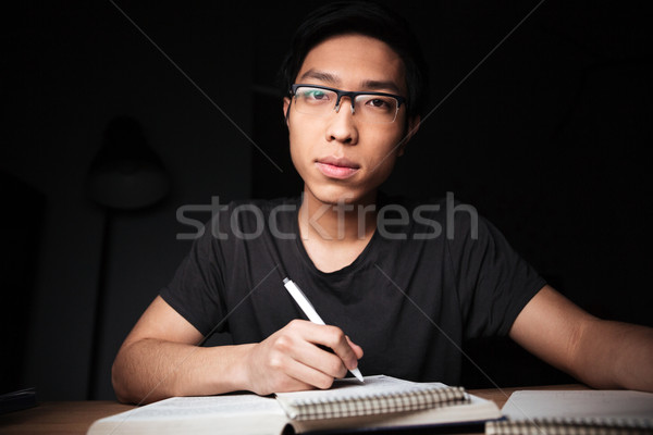 Pensive man in glasses studying and writing at the table  Stock photo © deandrobot