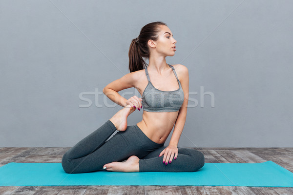 Young woman doing yoga exercise one legged king pigeon Stock photo © deandrobot