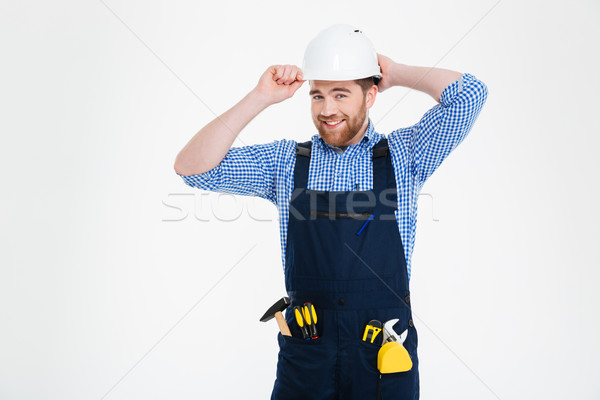 Portrait of happy bearded young builder in overall and helmet Stock photo © deandrobot