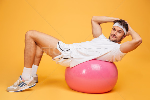 Sportsman doing abs on fitness ball over orange background Stock photo © deandrobot