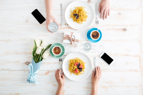 Hands of couple eating pasta and drinking water on table Stock photo © deandrobot