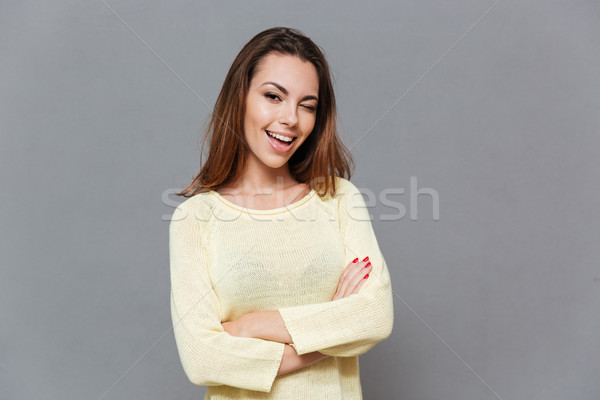 Stock photo: Young woman in sweater standing with arms folded and winking