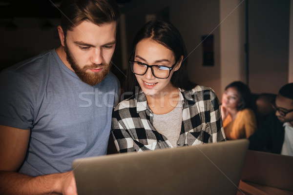 Happy business people working at night in office with laptop Stock photo © deandrobot