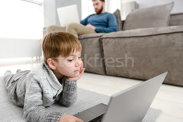 Little pretty child using laptop while lies in floor indoors Stock photo © deandrobot