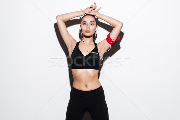 Beautiful young sportswoman with armband listening to musing using earphones Stock photo © deandrobot