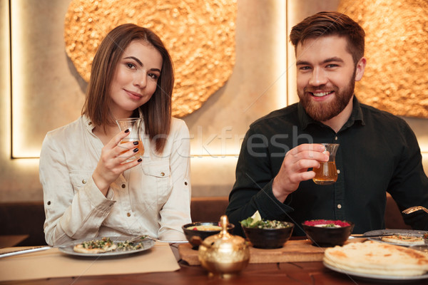 ?heerful young loving couple sitting in cafe and eating Stock photo © deandrobot