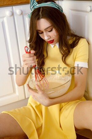 Sexy young pin-up lady sitting on floor and cooking. Stock photo © deandrobot
