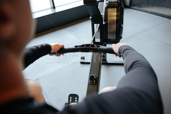 Blick zurück muskuläre Mann Rudern Maschine Fitnessstudio Stock foto © deandrobot