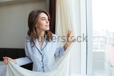 Fiatal nő függönyök néz kilátás fiatal nő Stock fotó © deandrobot
