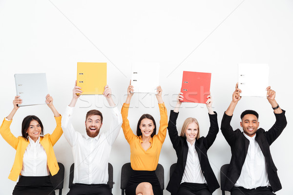 Cheerful colleagues sitting in office holding folders. Stock photo © deandrobot