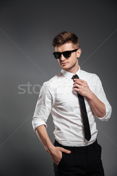 Handsome man in sunglasses and formalwear posing and looking away Stock photo © deandrobot