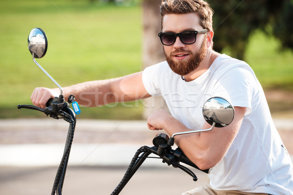 Cheerful bearded man in sunglasses sitting on modern motorbike Stock photo © deandrobot