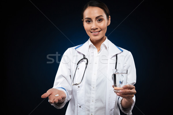 Young lady smiling to camera and holding pill and glass of water isolated Stock photo © deandrobot