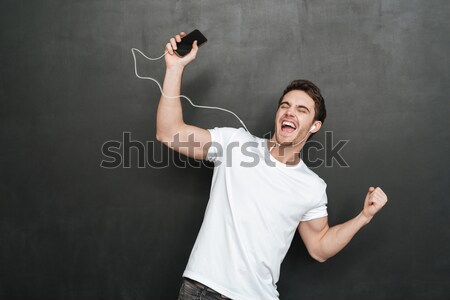 Portrait of successful guy in white shirt rejoicing like winner  Stock photo © deandrobot