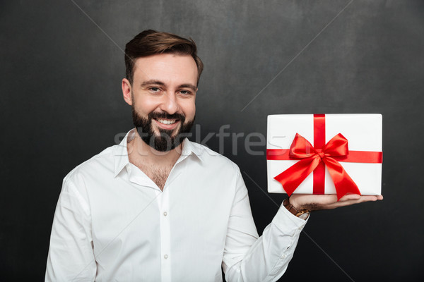 Portrait of happy brunette man demonstrating white present box w Stock photo © deandrobot