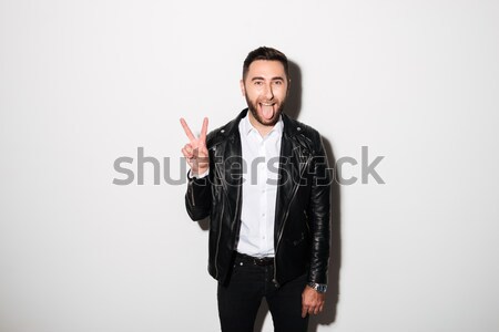 Portrait of a cheery man in jacket showing peace gesture Stock photo © deandrobot
