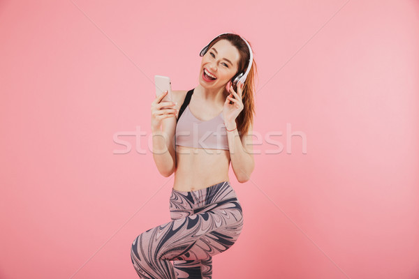 Happy sportswoman in headphones listening music and enjoys Stock photo © deandrobot