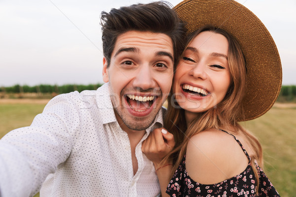 Photo of joyous young man and woman laughing, and taking selfie  Stock photo © deandrobot